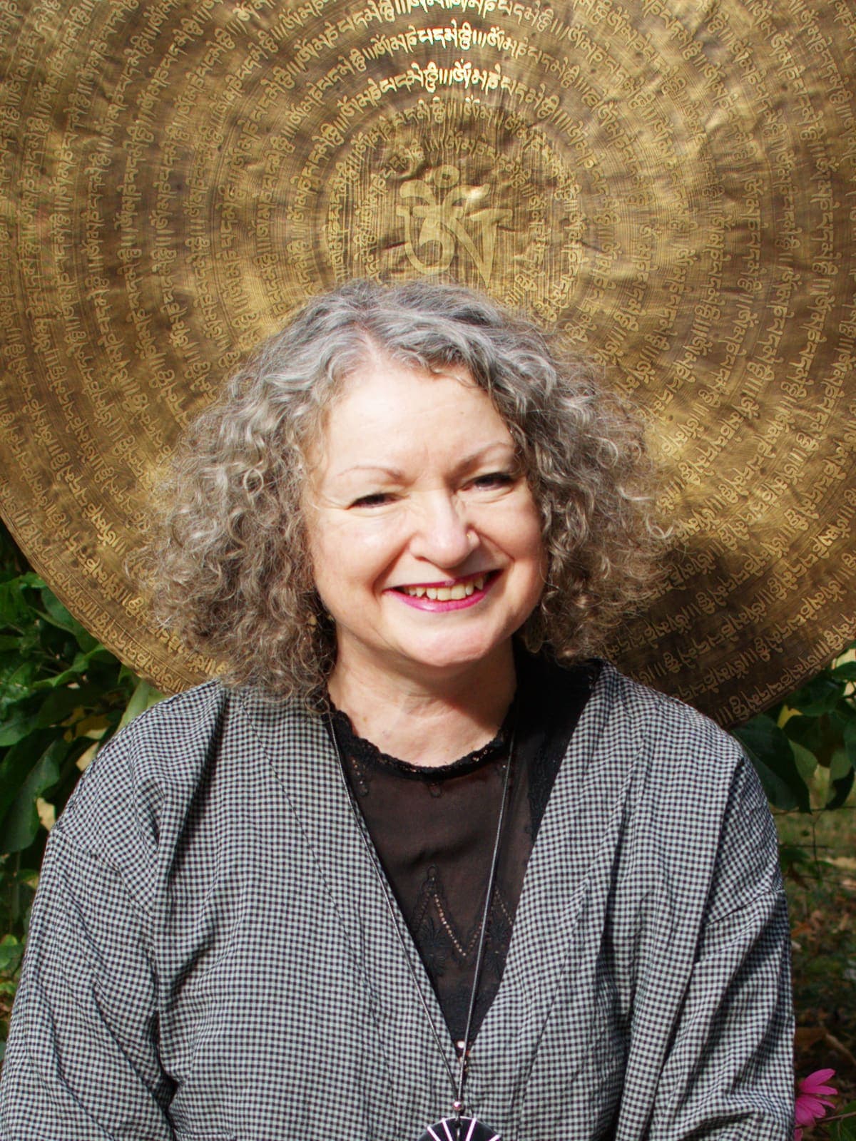 Rachel Swallow, Gong Practitioner offering sound therapy and gong baths in North Wales, seated in front of a Tibetan gong